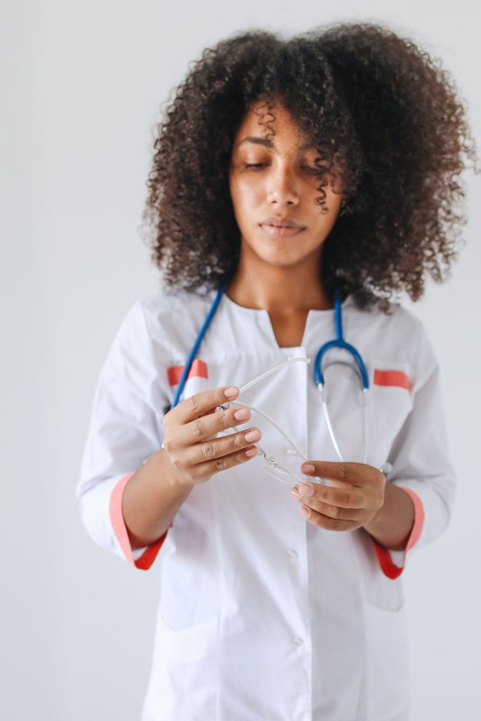 Crafting Captivating Headlines: Your awesome post title goes here Young female doctor with curly hair holding eyeglasses and wearing a stethoscope.